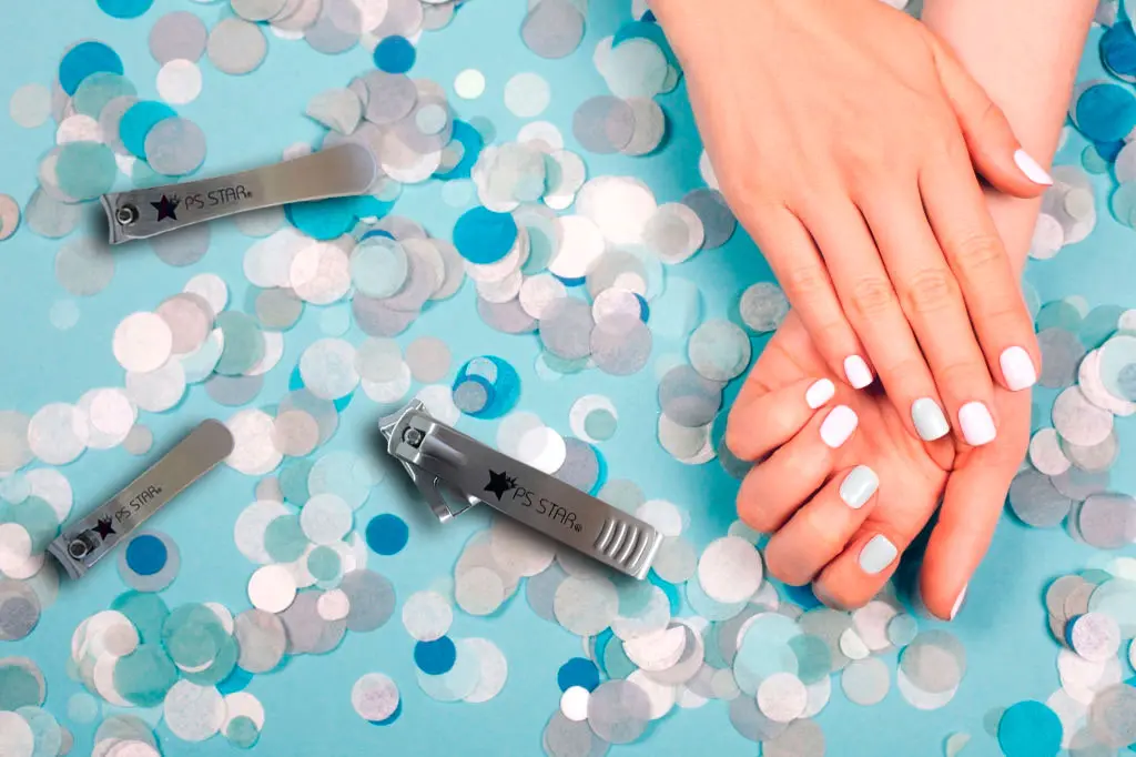 Three stainless steel nail clippers beside manicured hands on a light blue confetti background.