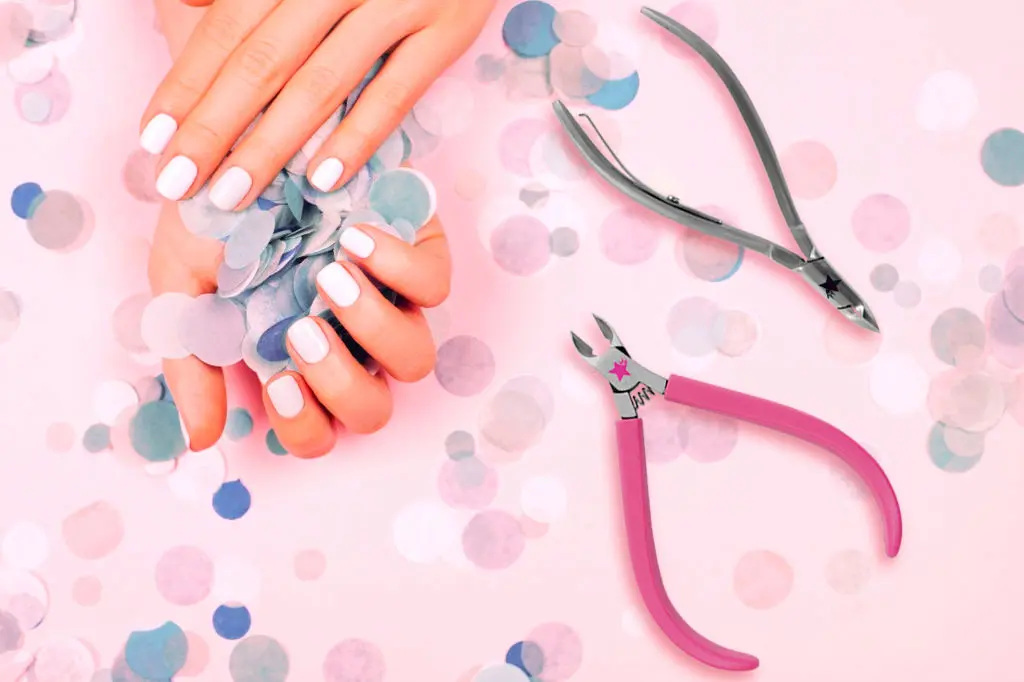 Two cuticle nippers shown with manicured hands on a pink confetti background.